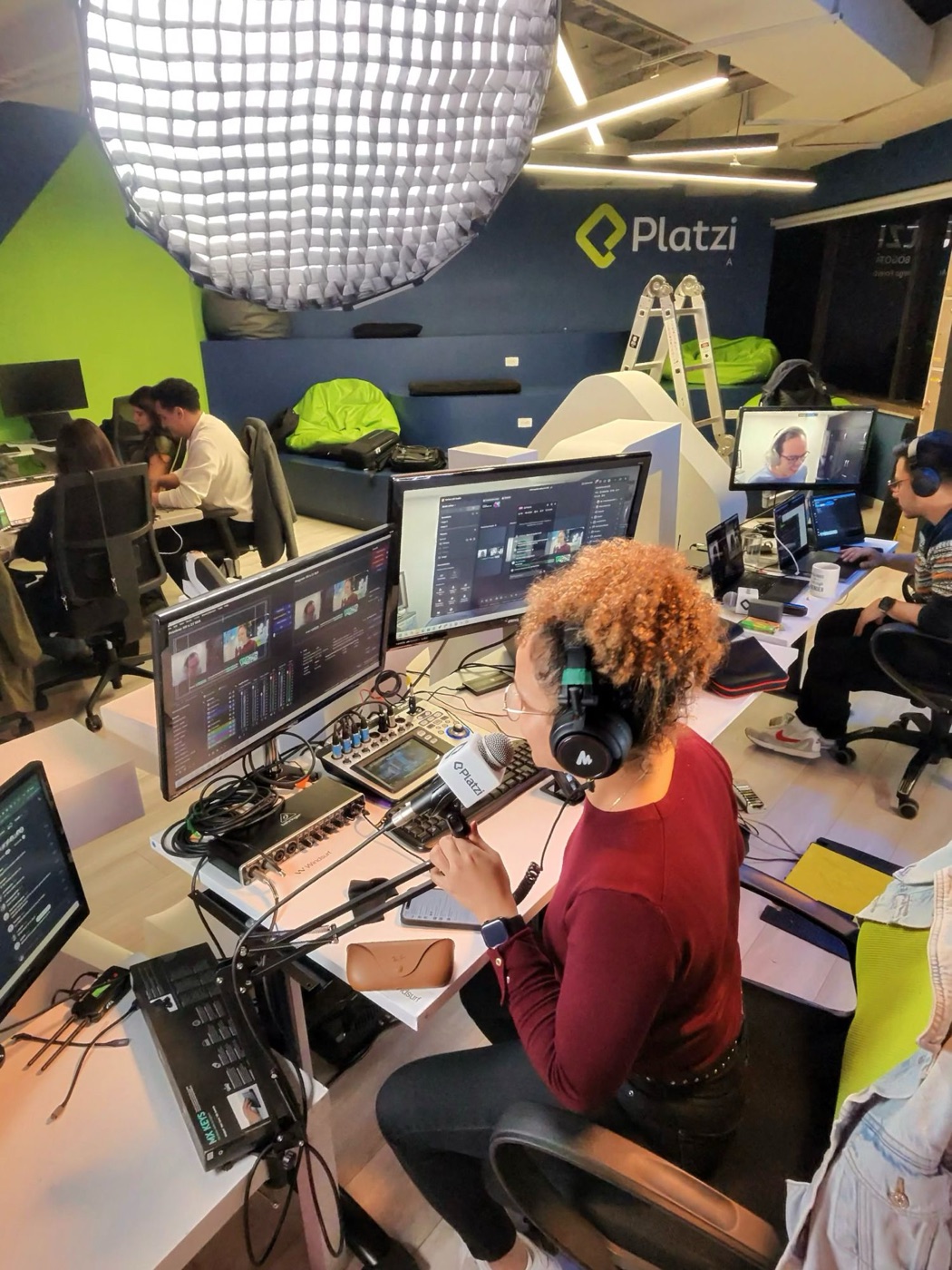 Transmisión en vivo desde el estudio: realizadora con audífonos y micrófono frente a los monitores de control